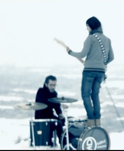 Drummist has a big drum, so the guitarist is standing on it and facing towards the drummist while playing.